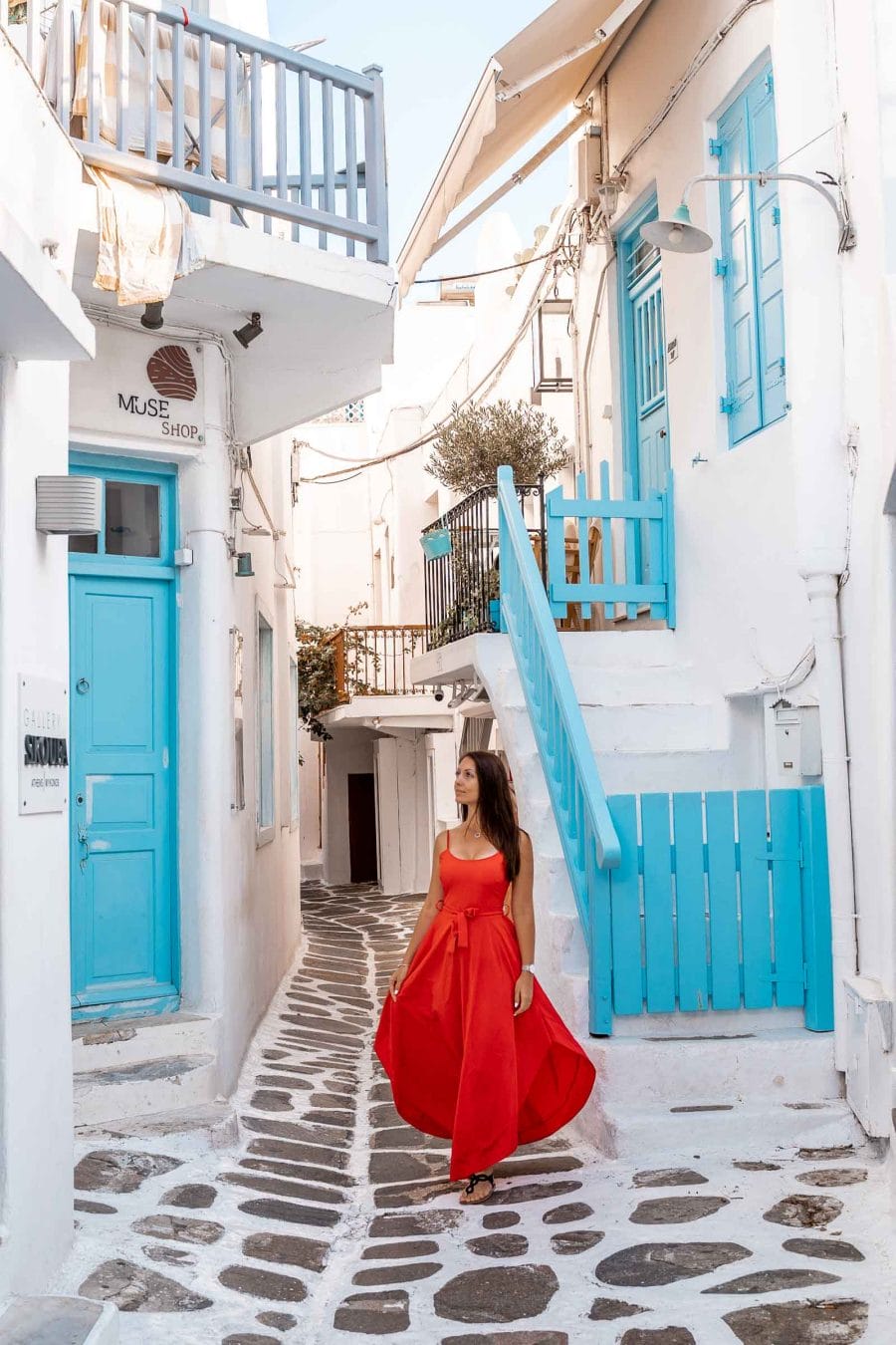 Girl in a red dress standing in the middle of a blue street in Mykonos