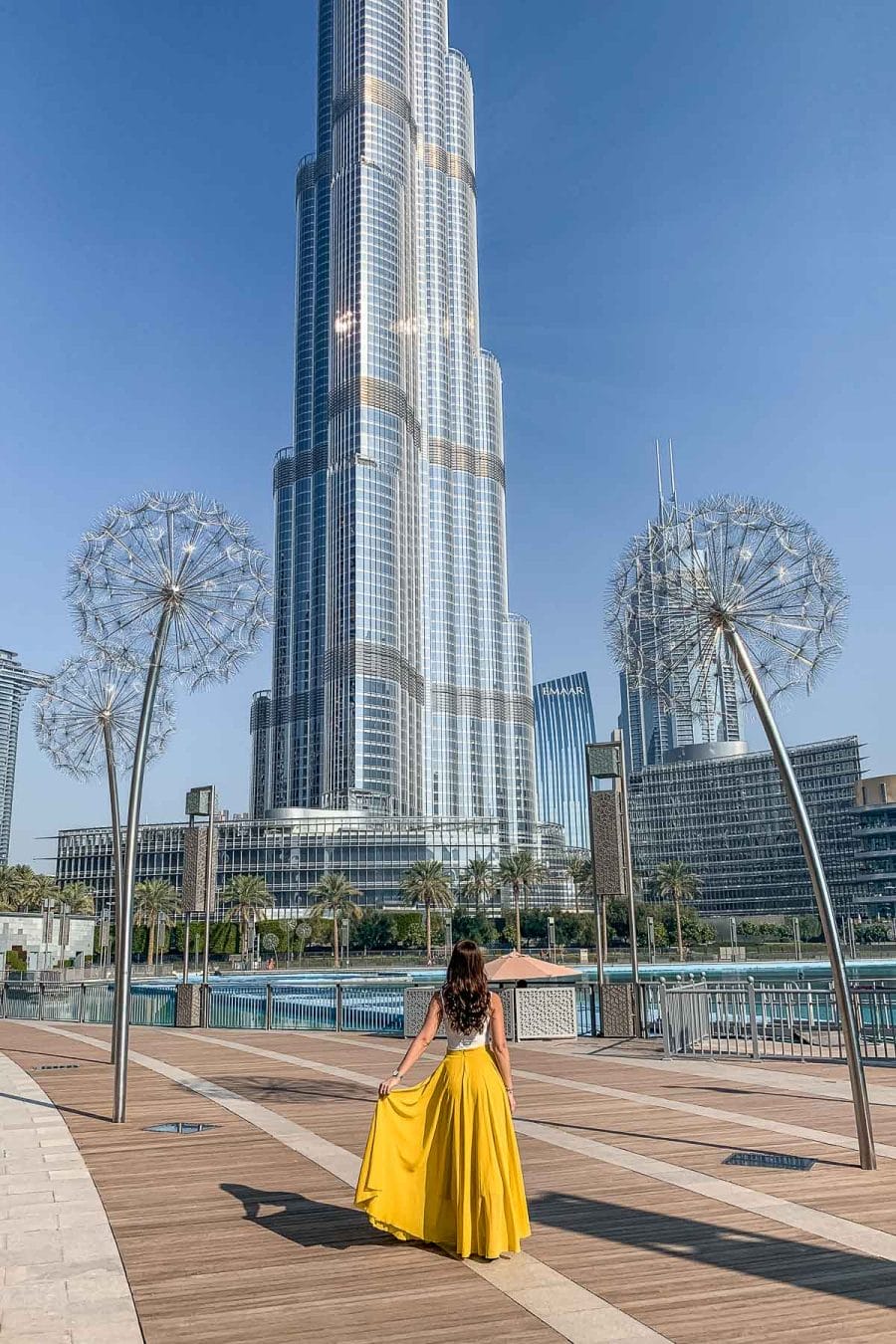 Girl in yellow skirt standing in the Burj Park by Emaar in Dubai with the Burj Khalifa in the background