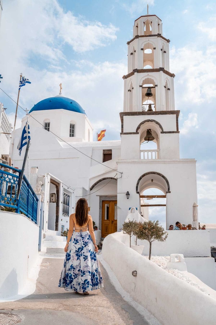 Girl in a blue floral dress standing in front of a church in Pyrgos, Santorini