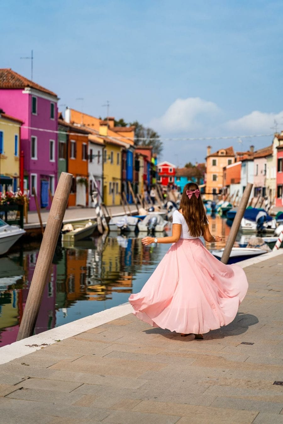 Girl in a pink skirt twirling in front of the colorful houses in Burano