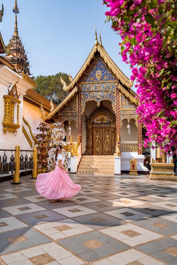Girl in a pink skirt twirling in front of a beautiful temple in Doi Suthep, Chiang Mai