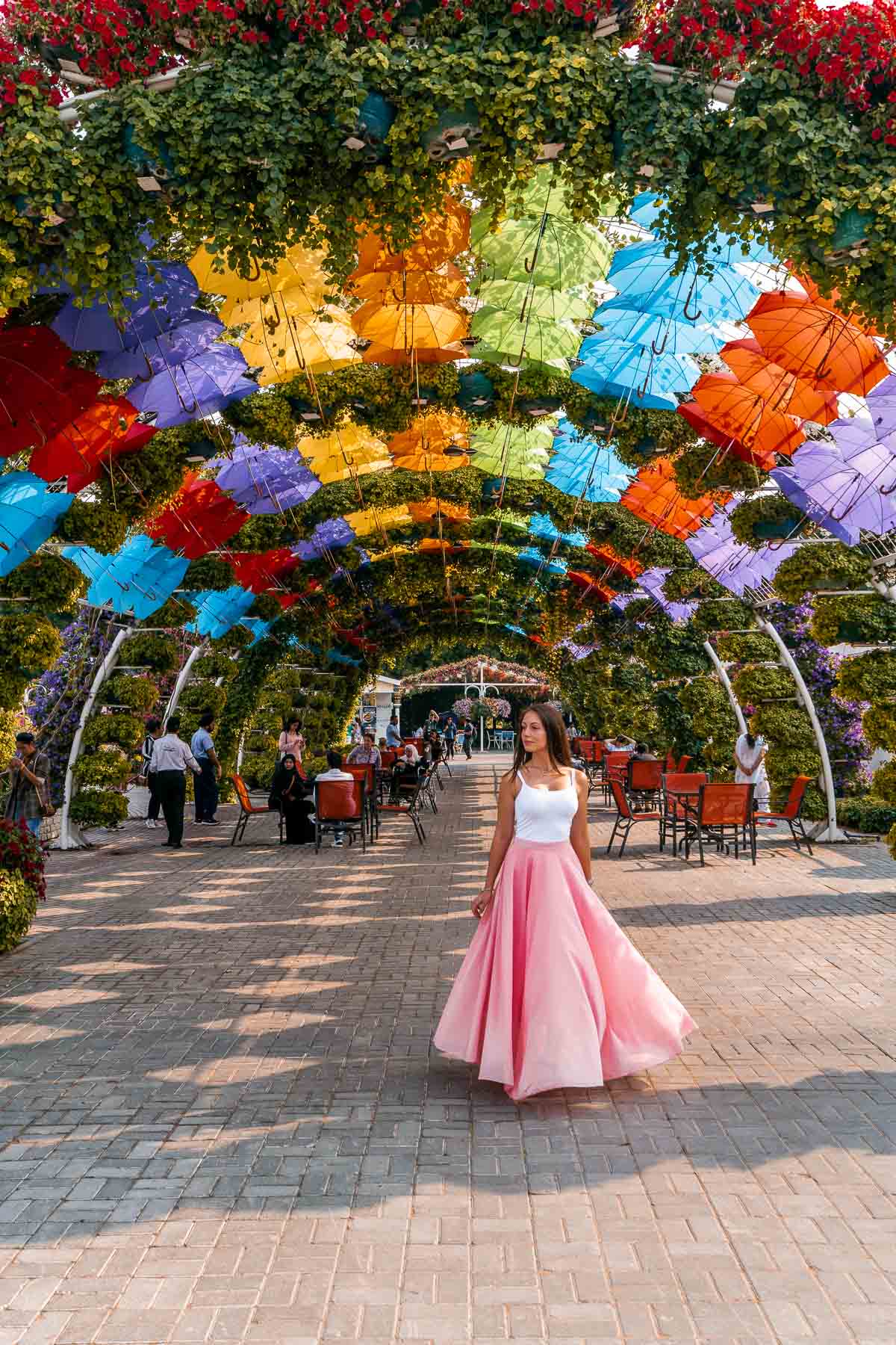 Girl in a pink skirt standing under colorful umbrellas in the Dubai Miracle Garden