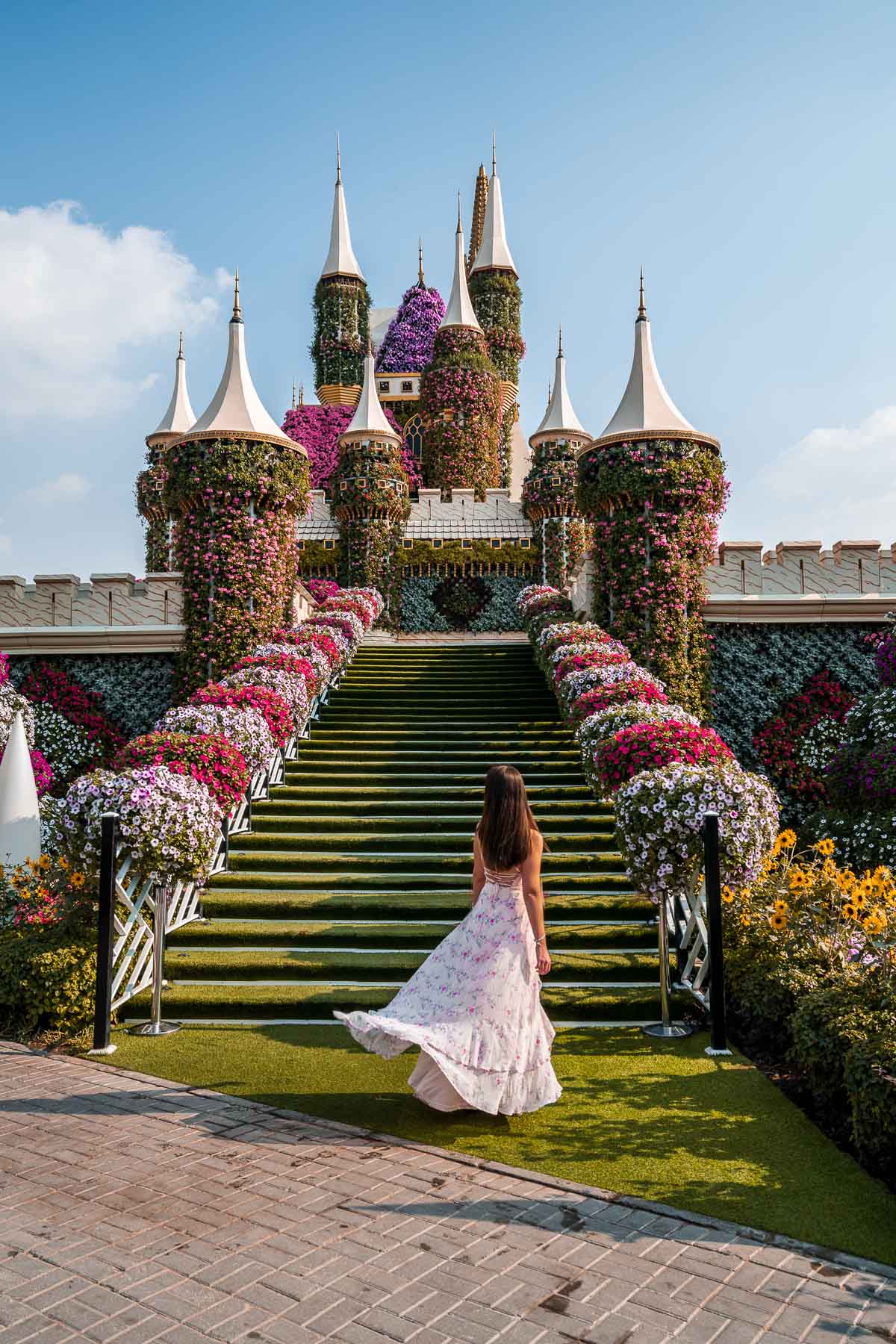 Girl in pink floral dress standing in front of a castle made of flowers in the Dubai MIracle Garden
