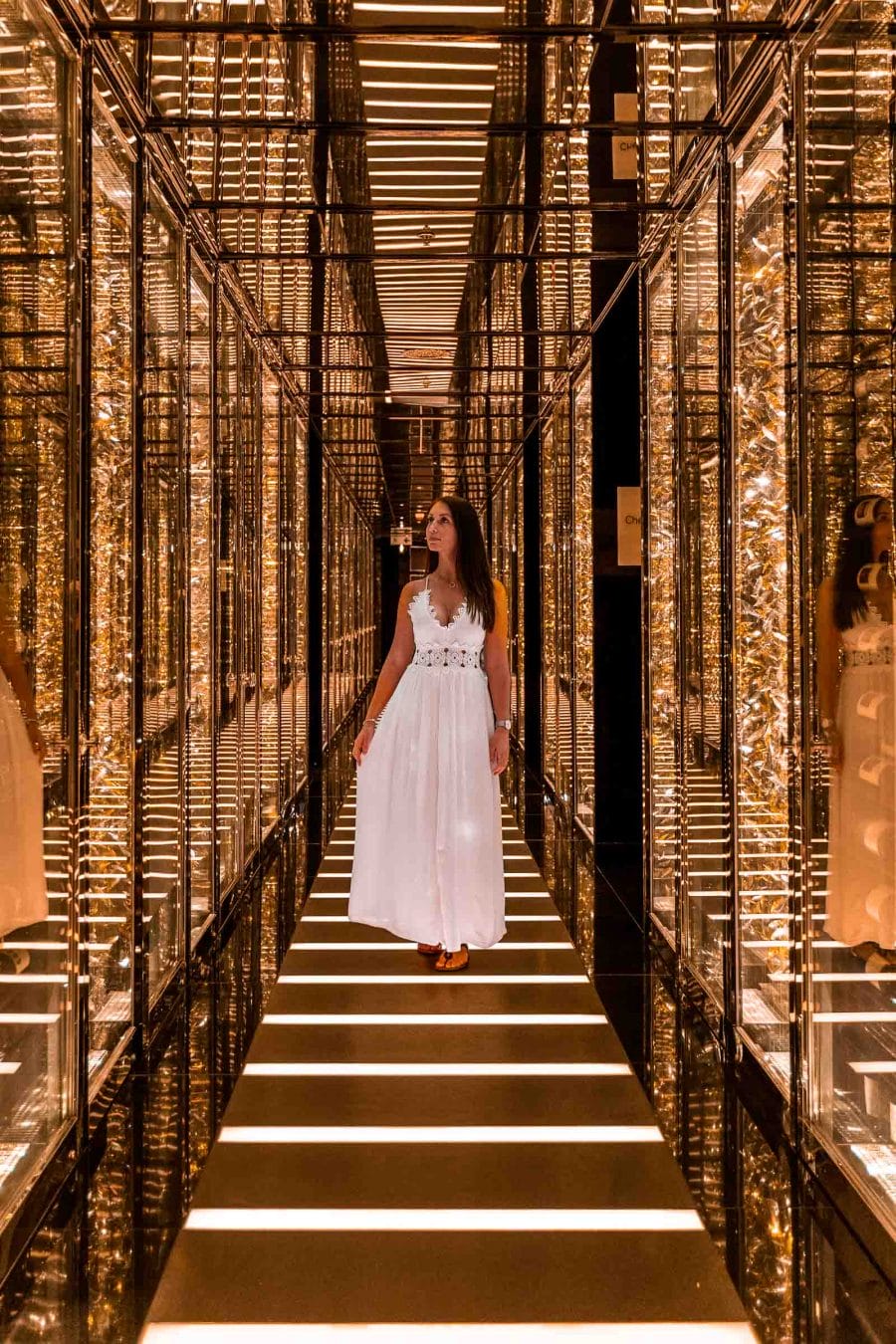 Girl in white dress standing in the middle of a golden corridor