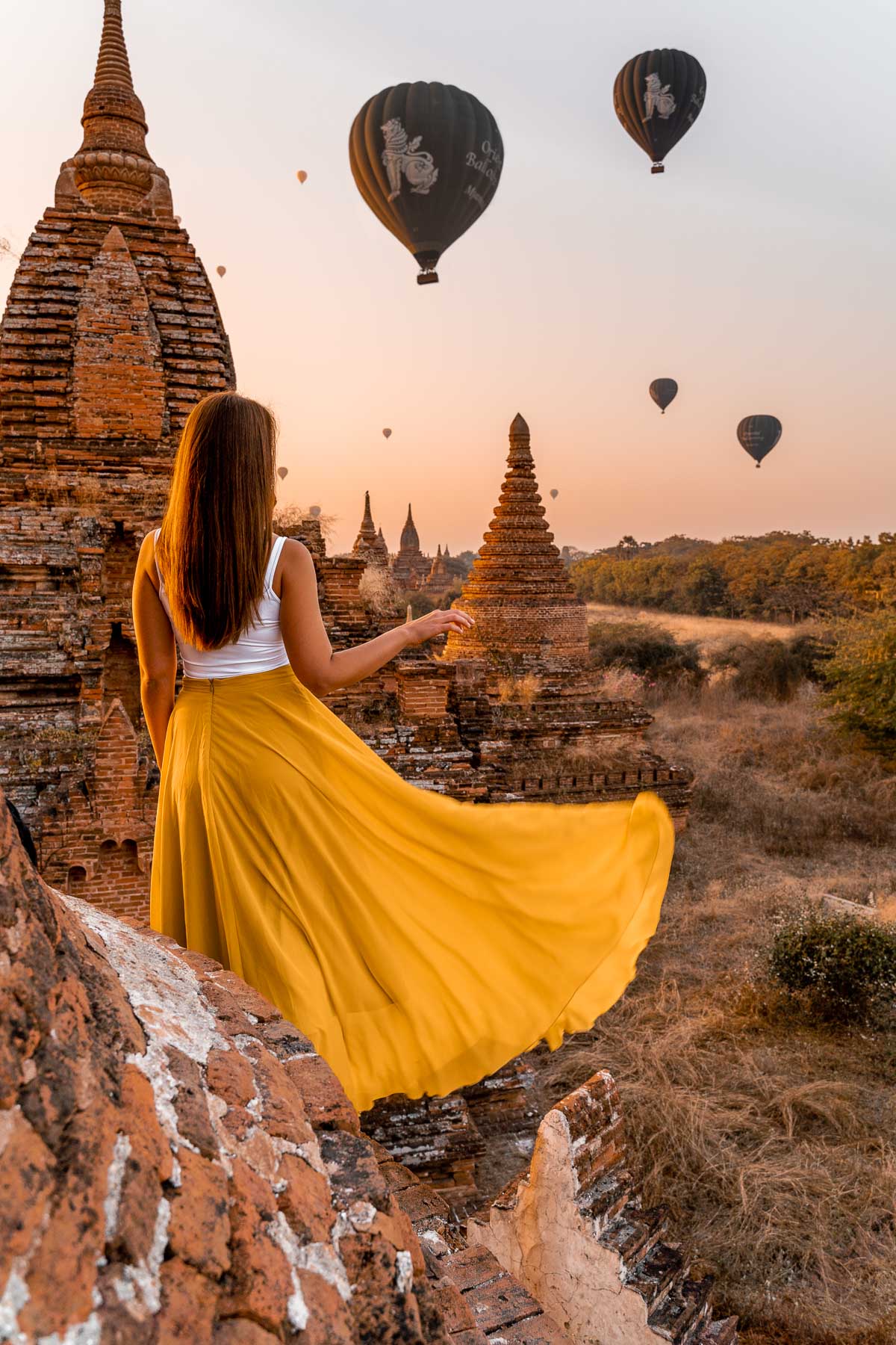 Girl in a yellow dress watching the hot air balloons at sunrise in Bagan, Myanmar