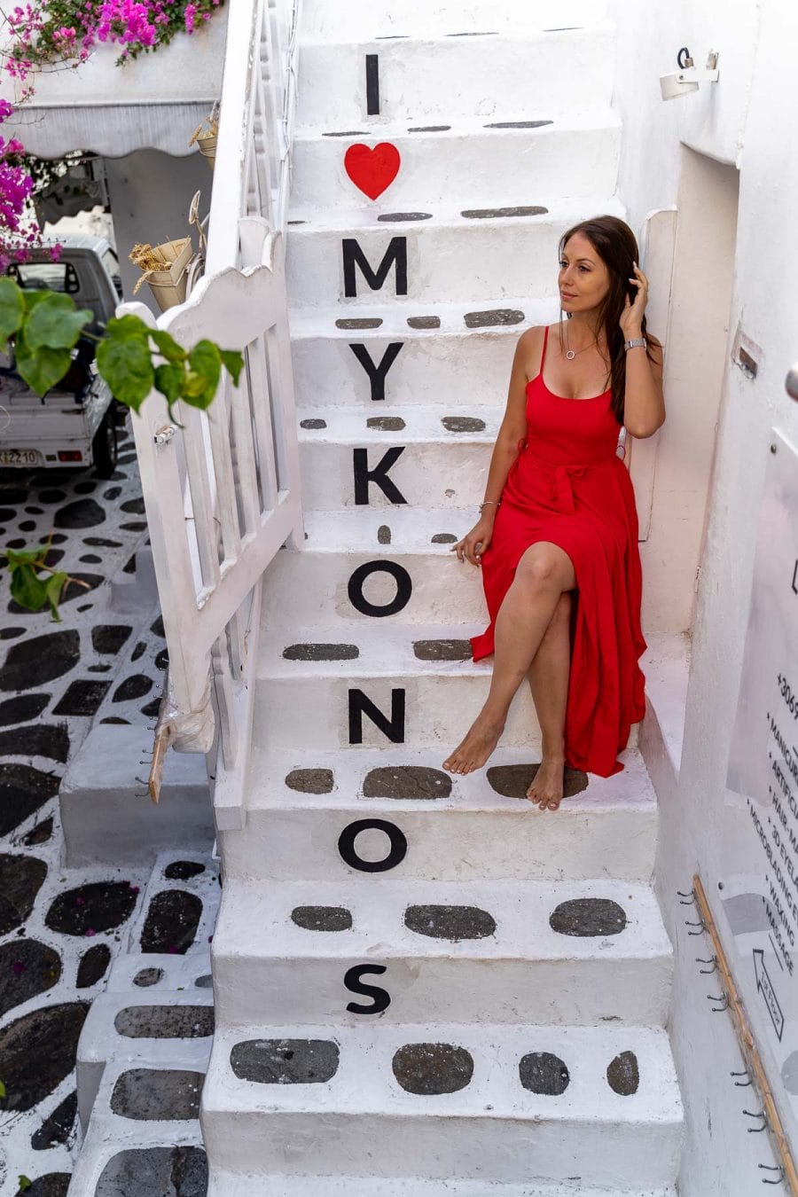 Girl in a red dress sitting on the I Love Mykonos stairway