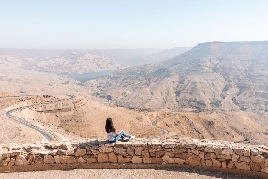Girl in a white T-shirt and jeans looking at the winding roads of the King's Highway in Jordan