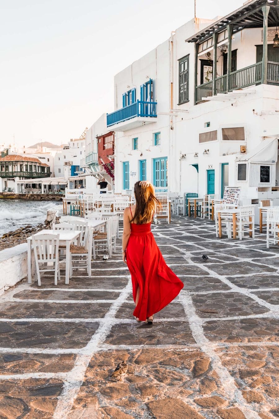 Girl in a red dress standing in the street at Little Venice in Mykonos Town
