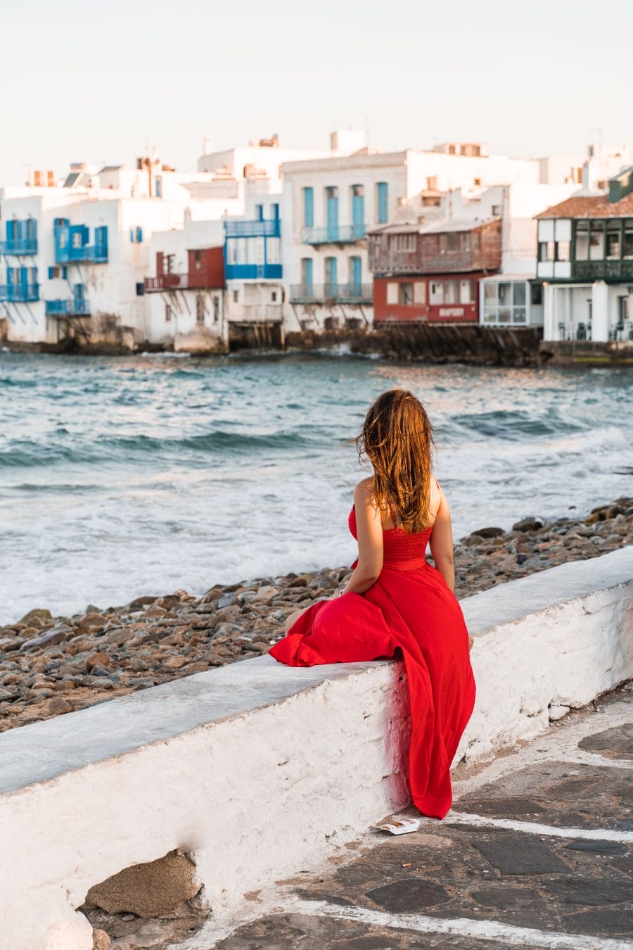 Girl in a red dress sitting at Little Venice in Mykonos Town