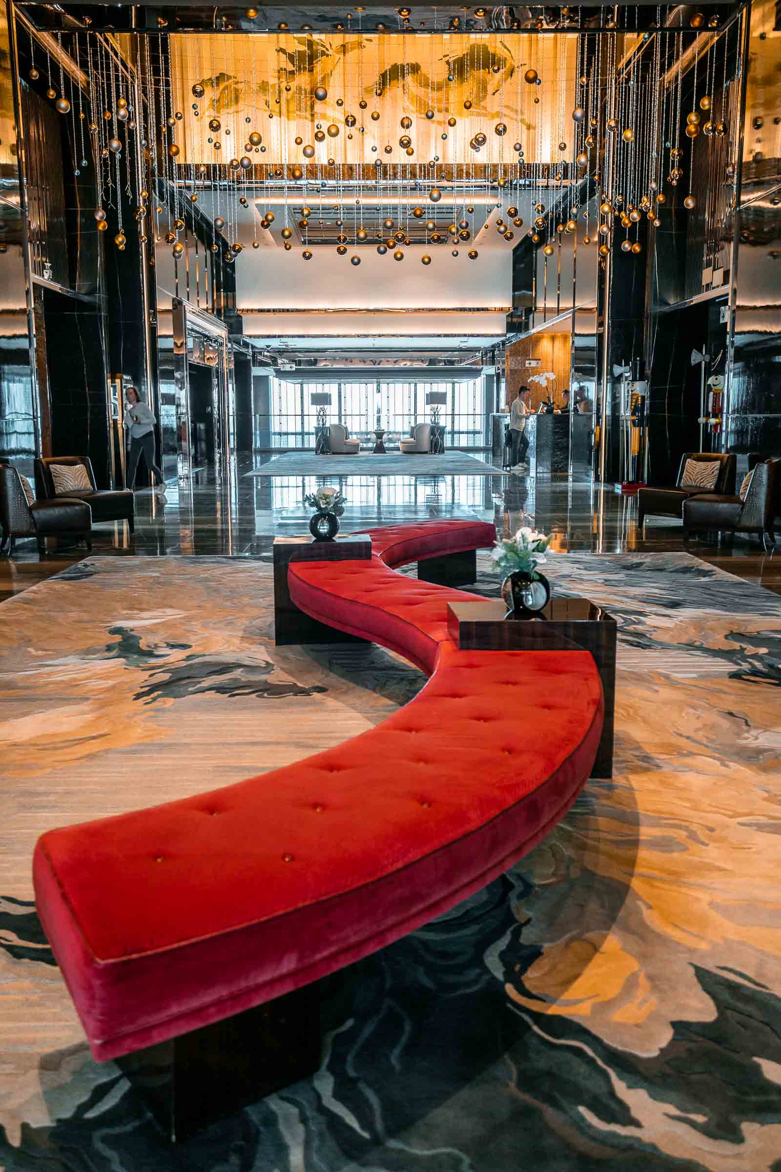 Lobby in the Ritz Carlton Hong Kong with a golden and dark marble design and a big red sofa