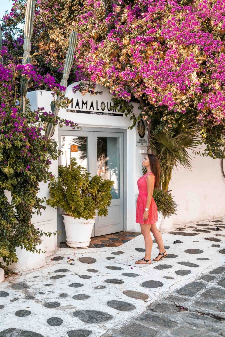 Girl in a pink dress standing in front of Mamalouka Restaurant in Mykonos