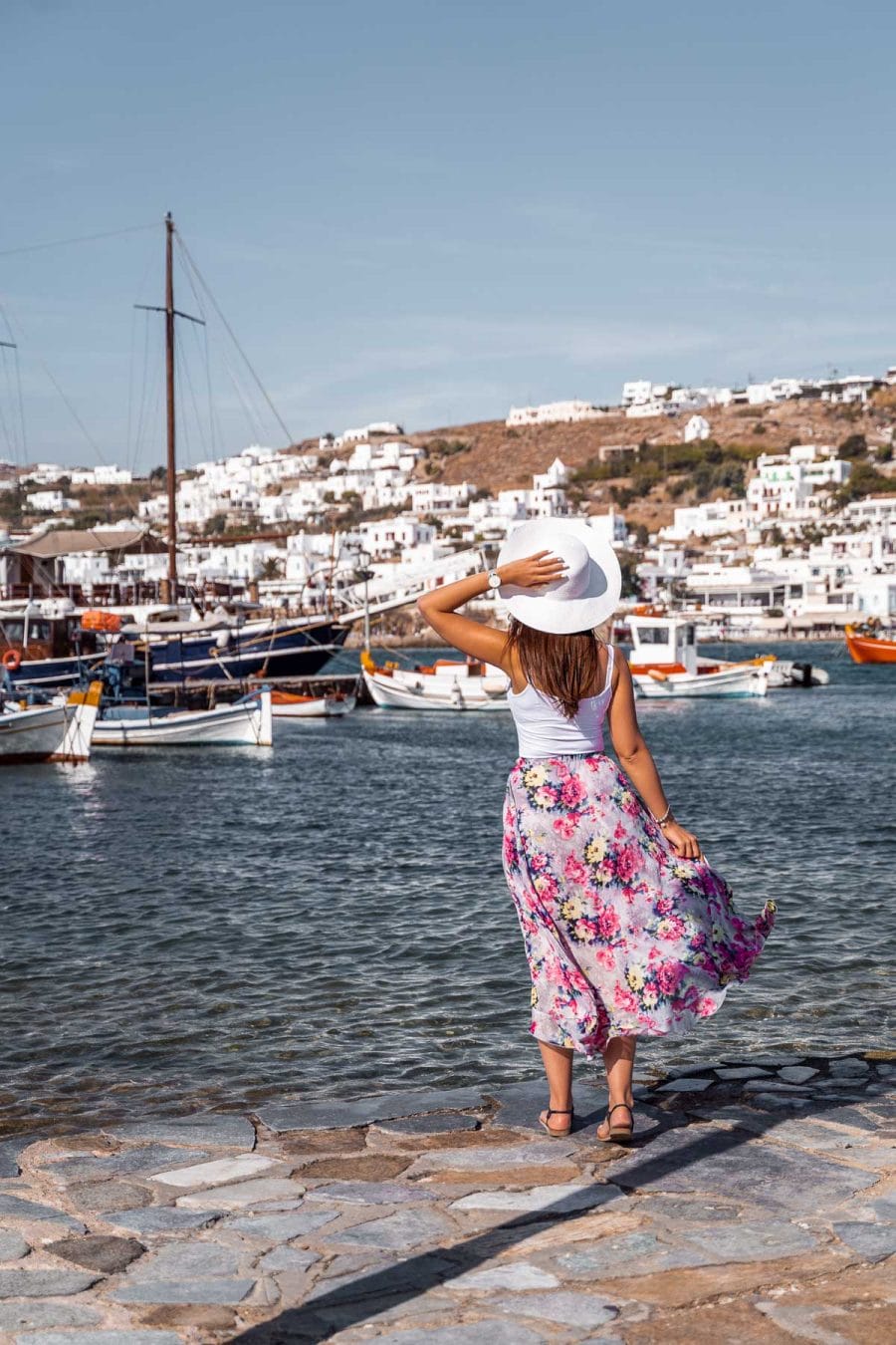 Girl in a purple floral dress standing in front of the Mykonos Harbour