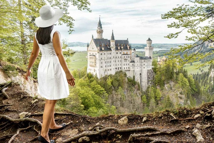 Girl in a white dress standing at the secret viewpoint at Neuschwanstein Castle
