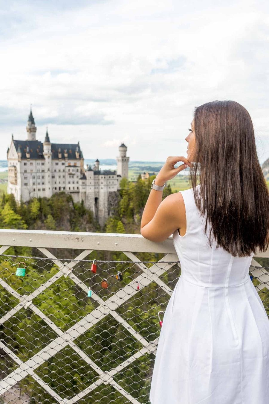 Girl in a white dress looking at the Neuschwanstein Castle from the Marienbrücke
