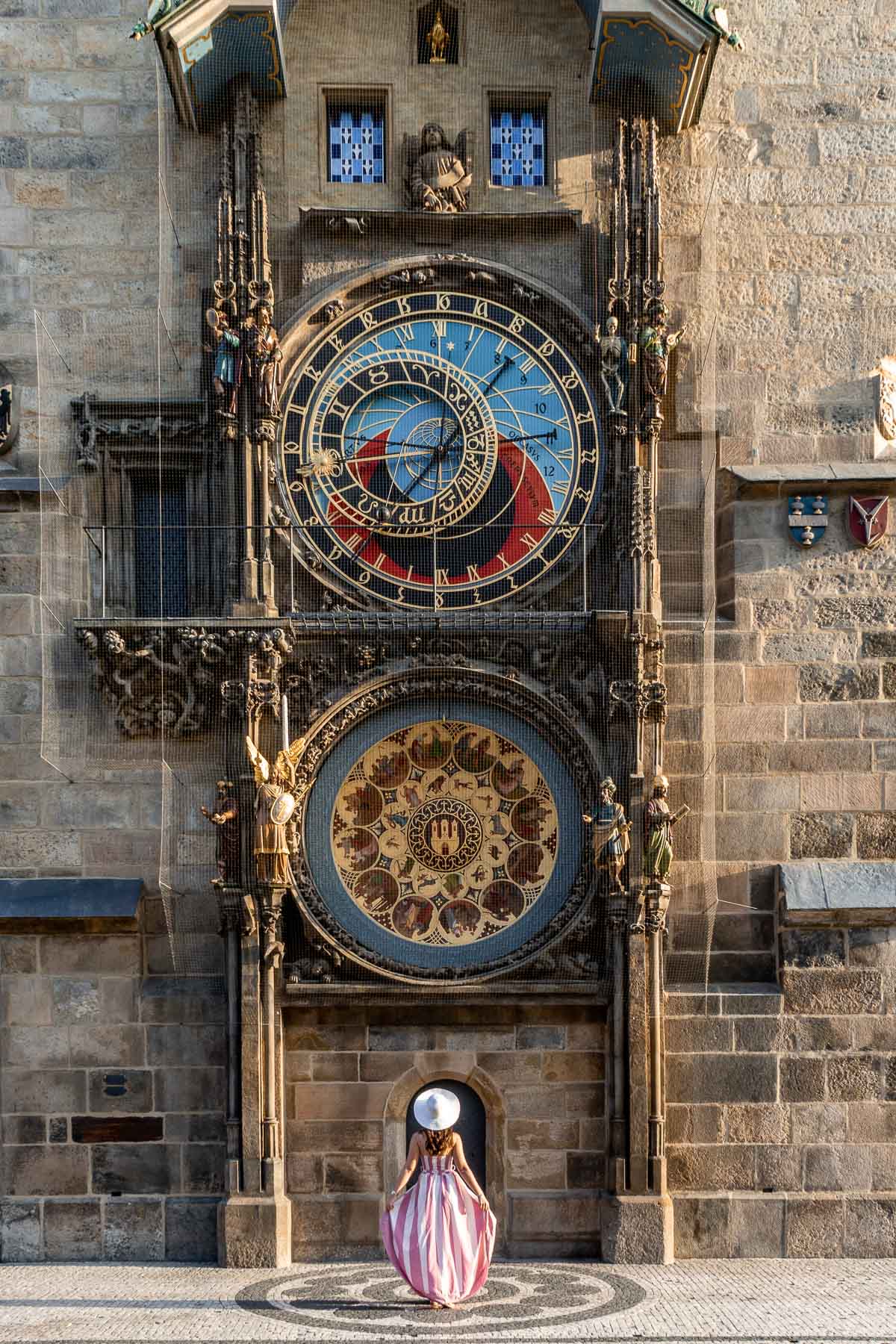 Girl in a pink dress standing in front of the Orloj Astronomical Clock in Prague