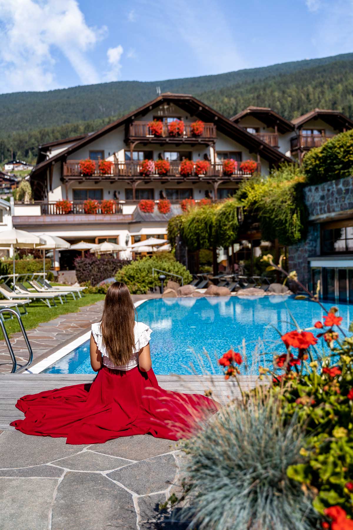 Girl in a red skirt sitting in front of the pool at Hotel Angelo Engel in Ortisei, Dolomites