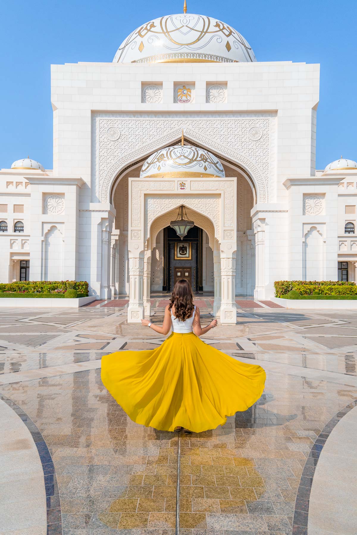 Girl in a yellow skirt twirling in front of Qasr Al Watan Palace in Abu Dhabi