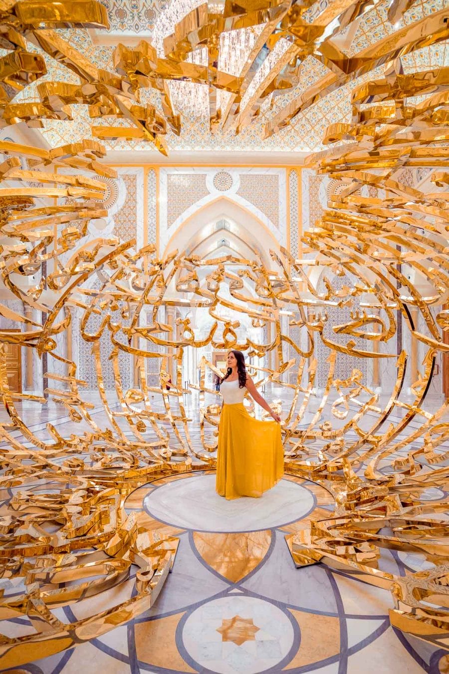 Girl in a yellow skirt standing in the middle of a golden structure in the Qasr Al Watan Palace Abu Dhabi