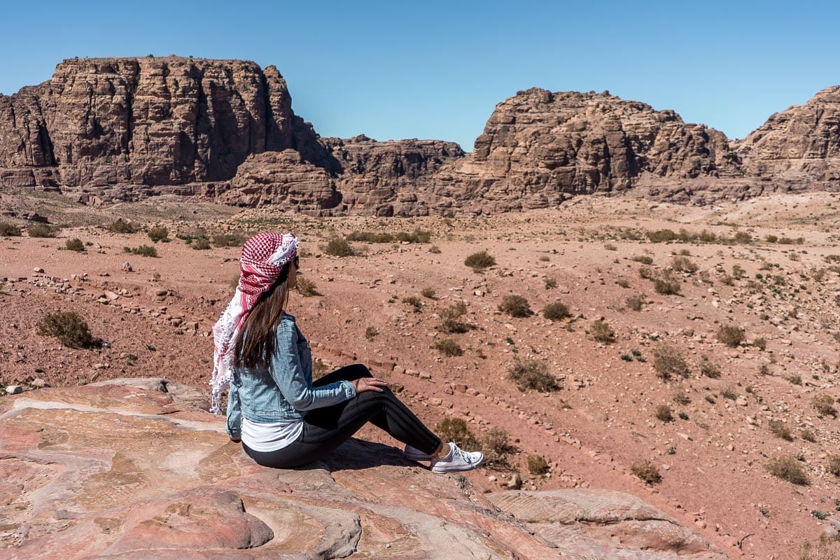 Girl in a denim jacket and a white-red keffiyeh looking at the view in Petra, Jordan