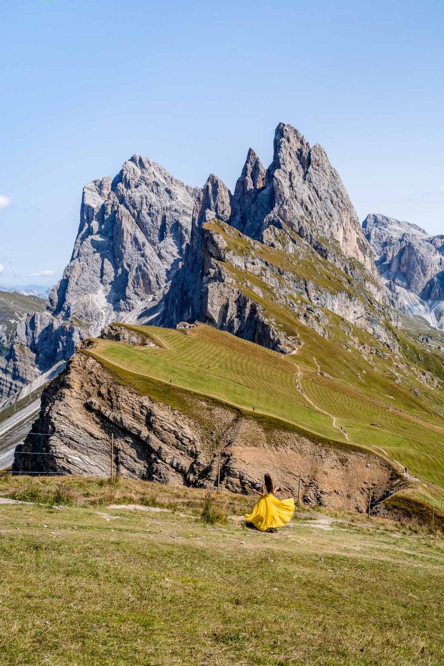 Girl in a yellow skirt standing in front of the Seceda Ridgeline, a must visit place on your Dolomites road trip itinerary