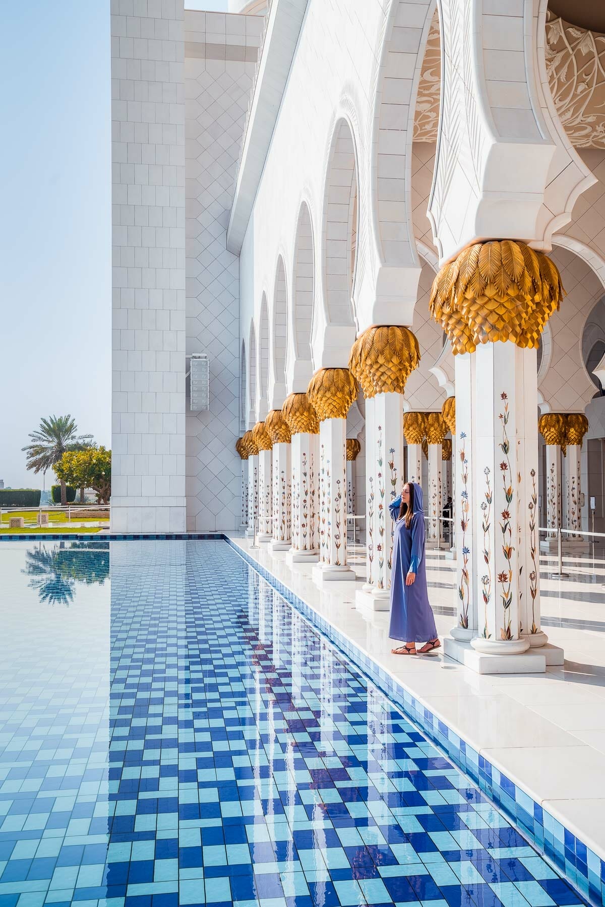 Girl in a blue abaya standing by the pool in Sheikh Zayed Grand Mosque, Abu Dhabi
