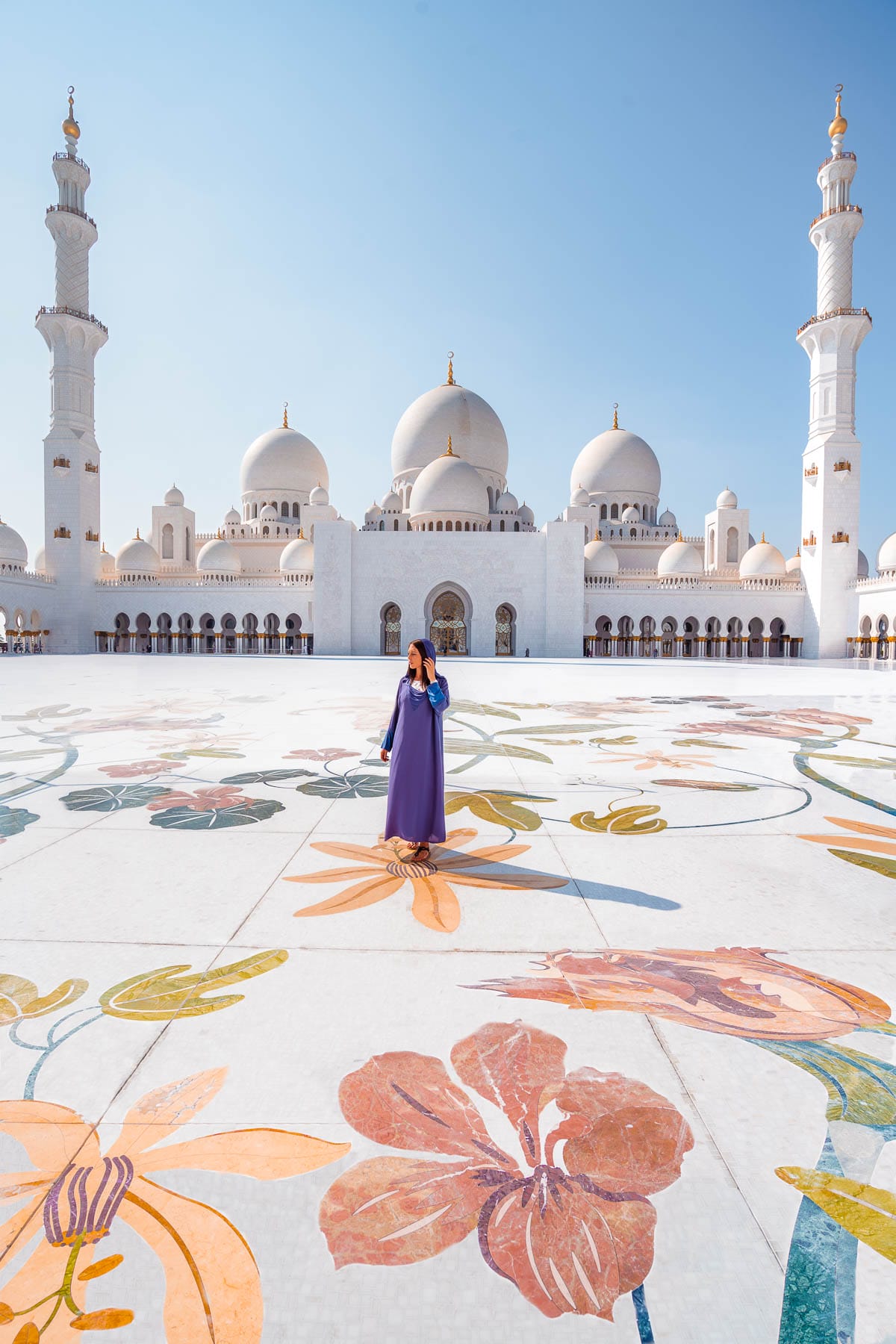 Girl in a blue abaya standing in the middle of Sheikh Zayed Grand Mosque, one of the most Instagrammable places in Abu Dhabi