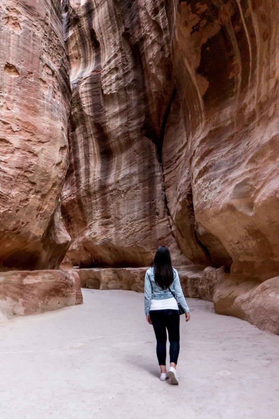 Girl in a denim jacket and jeans standing in the Siq at Petra, Jordan