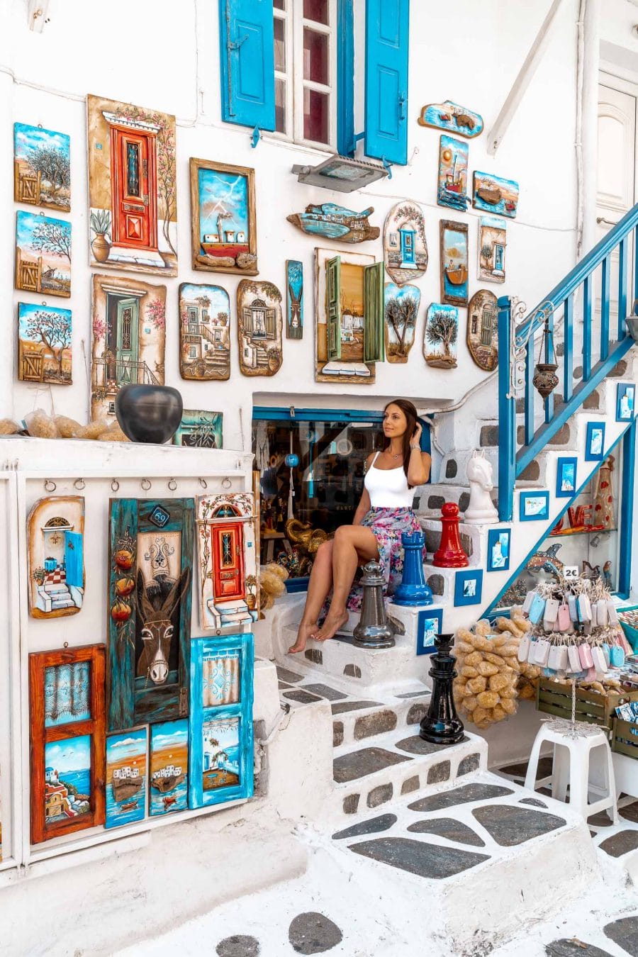 Girl sitting on a stairway in front of a cute souvenir shop in Mykonos