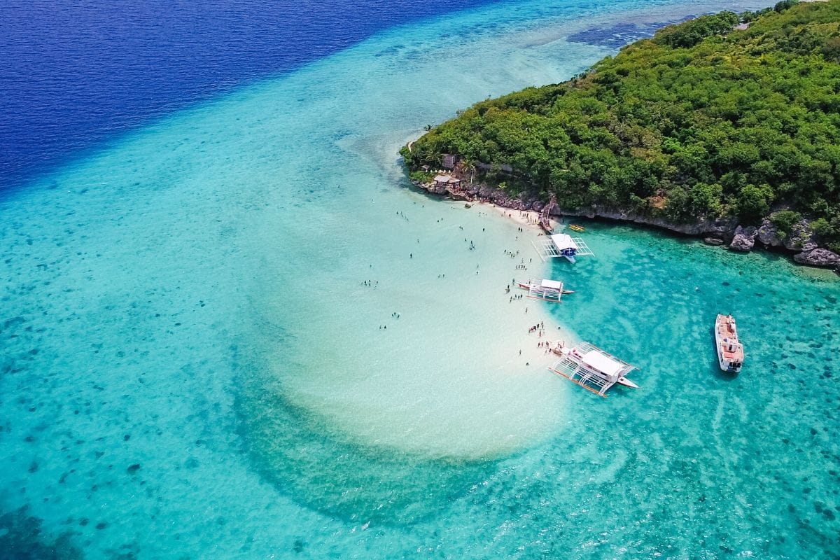 Tourists swimming in the crystal clear blue water at Sumilon Island, Philippines