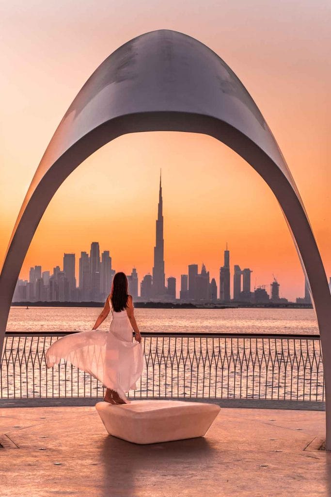 Girl in a white dress standing at the Dubai Creek Harbour at sunset (which is one of the most instagrammable places in Dubai)