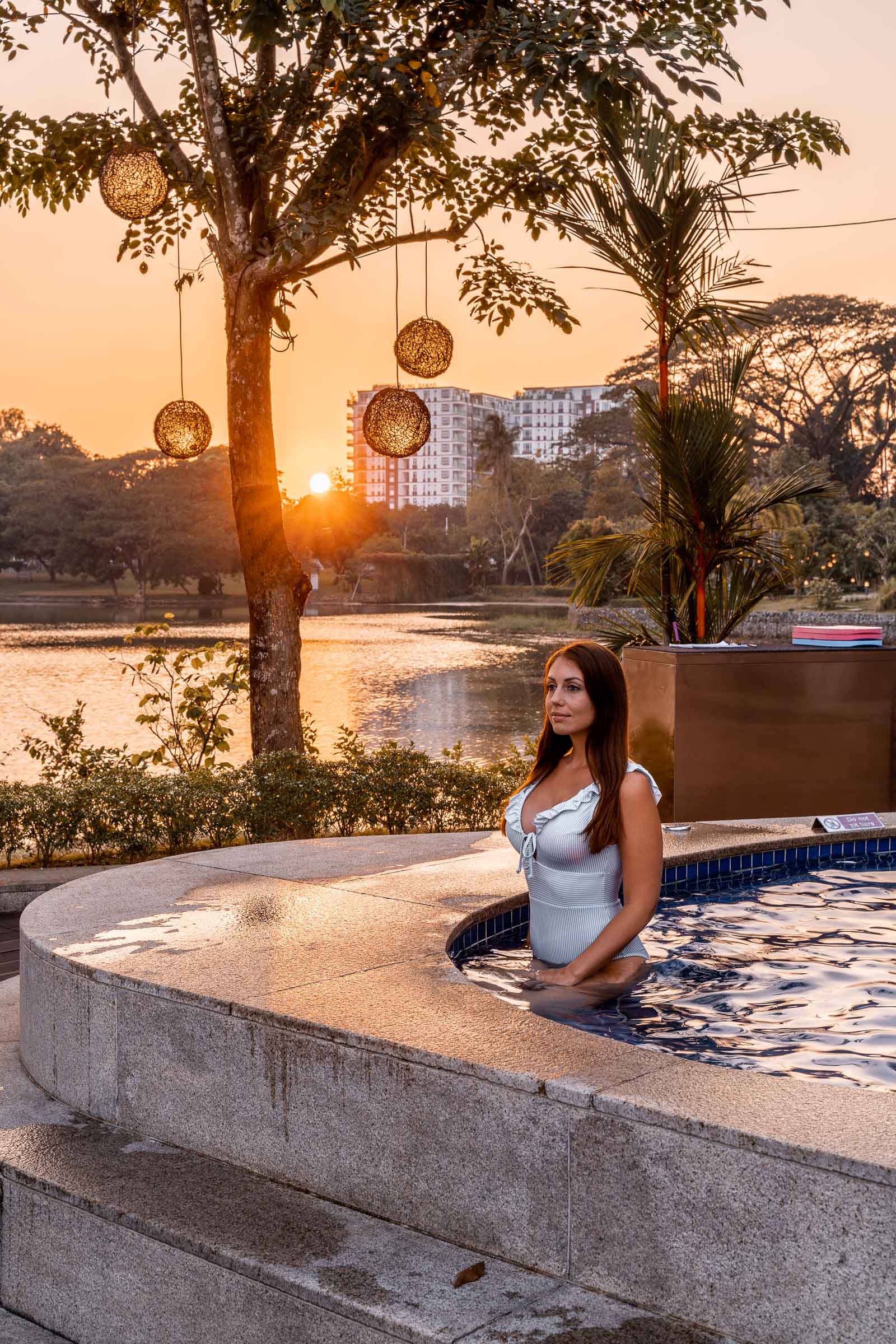 Girl in a blue bathing suit sitting in the hot tub watching the sunset at Lotte Hotel Yangon