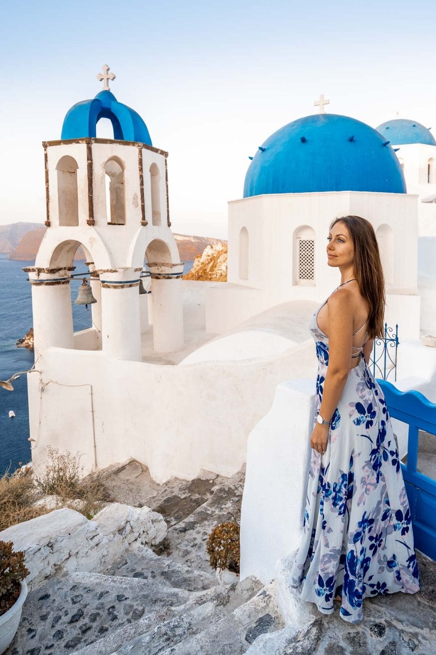 Girl in a blue dress standing in front of the three domes in Oia, Santorini