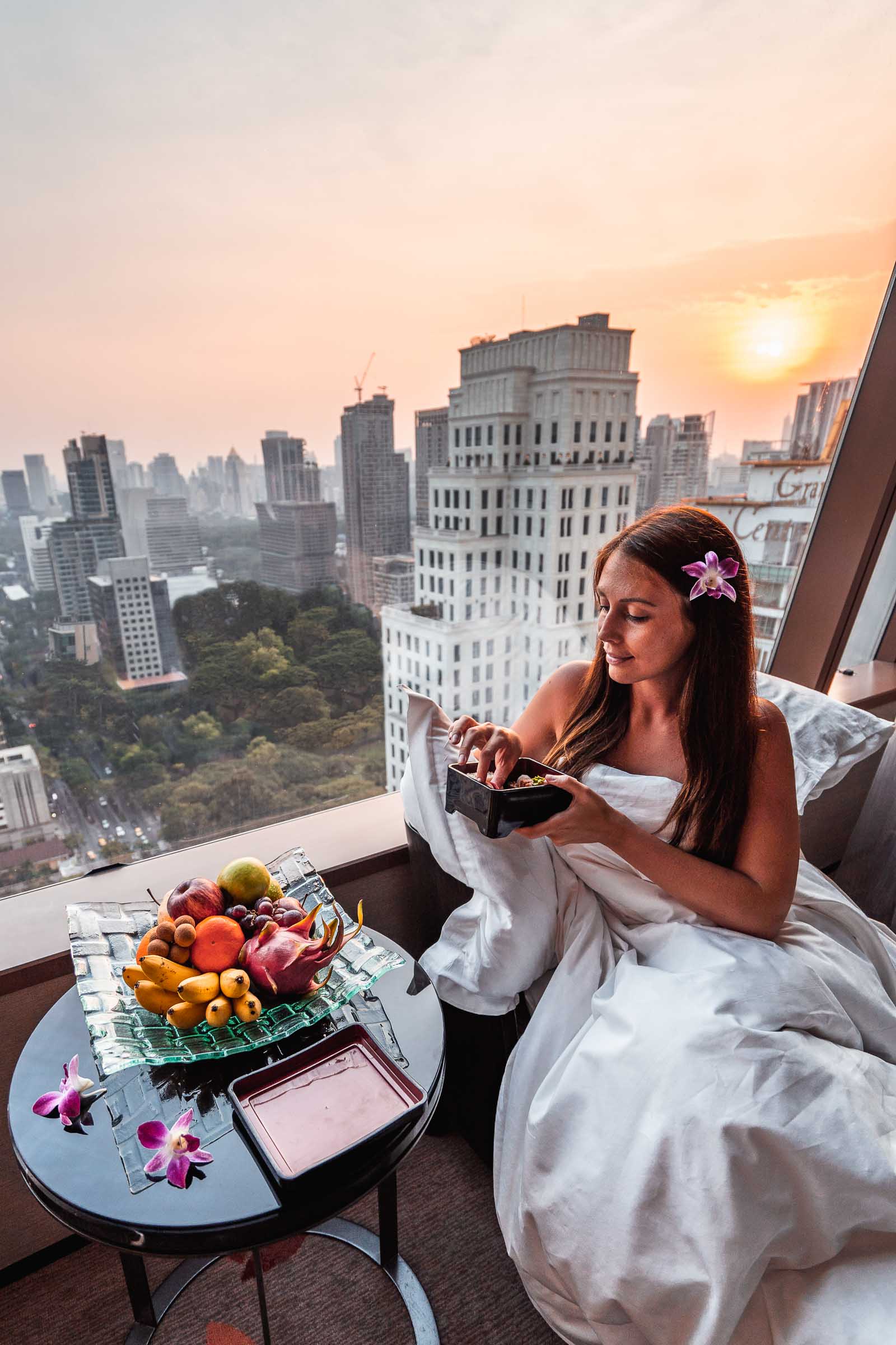 Girl eating breakfast with a view of the Bangkok skyline in the background in The Okura Prestige Bangkok