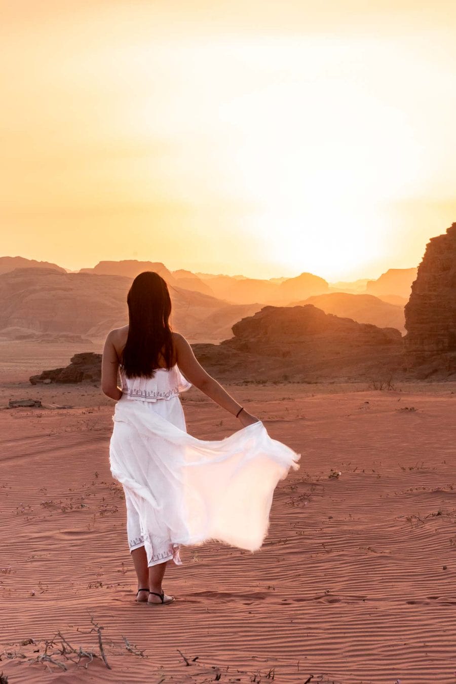 Girl in a white dress watching the sunset in the Wadi Rum, Jordan