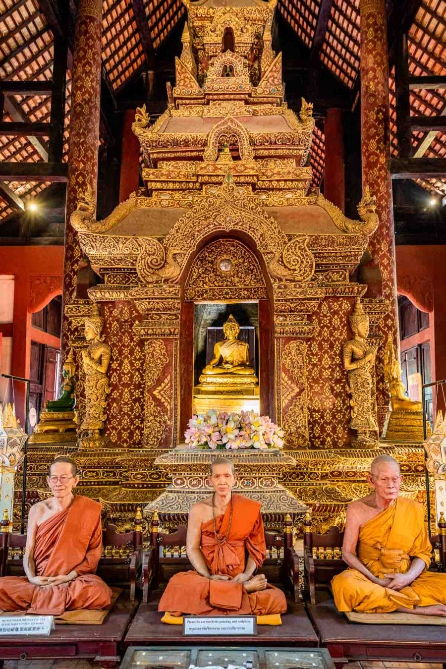 Monks made of vax sitting in front of a Buddha statue in Wat Phra Singh Temple in Chiang Mai