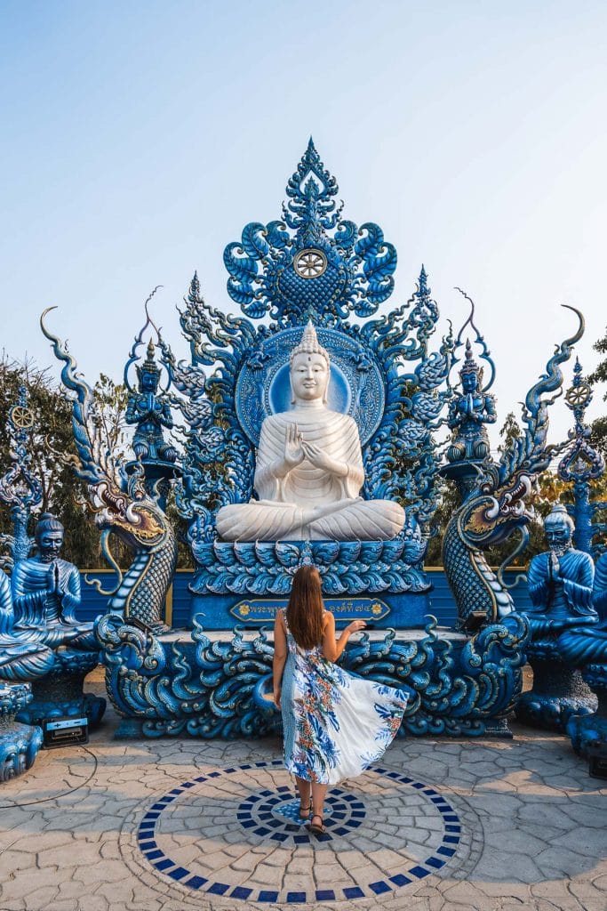Girl in a blue dress standing in front of a white Buddha statue at the Blue Temple in Chiang Rai
