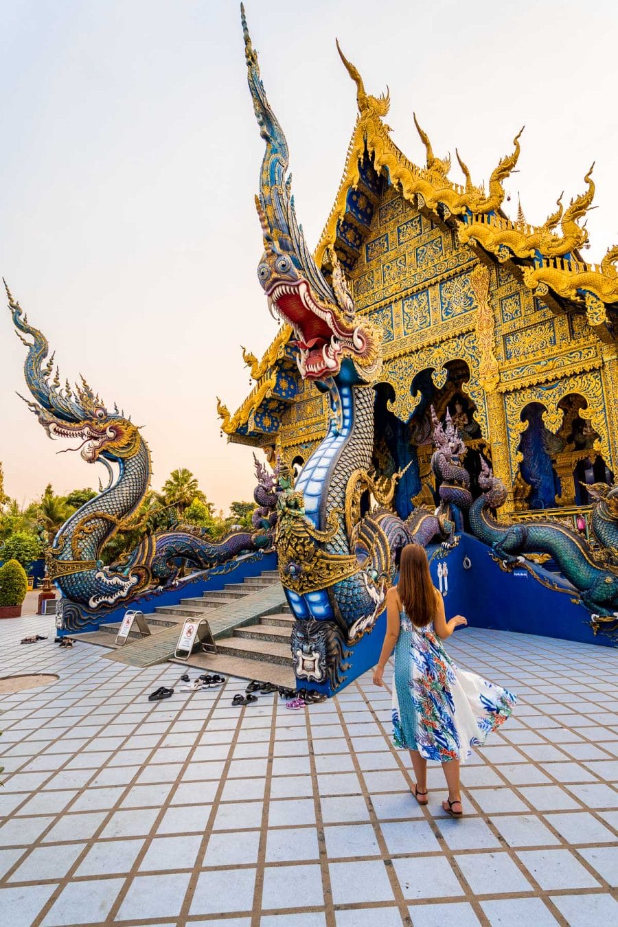 Girl in a blue dress standing in front of the Blue Temple in Chiang Rai