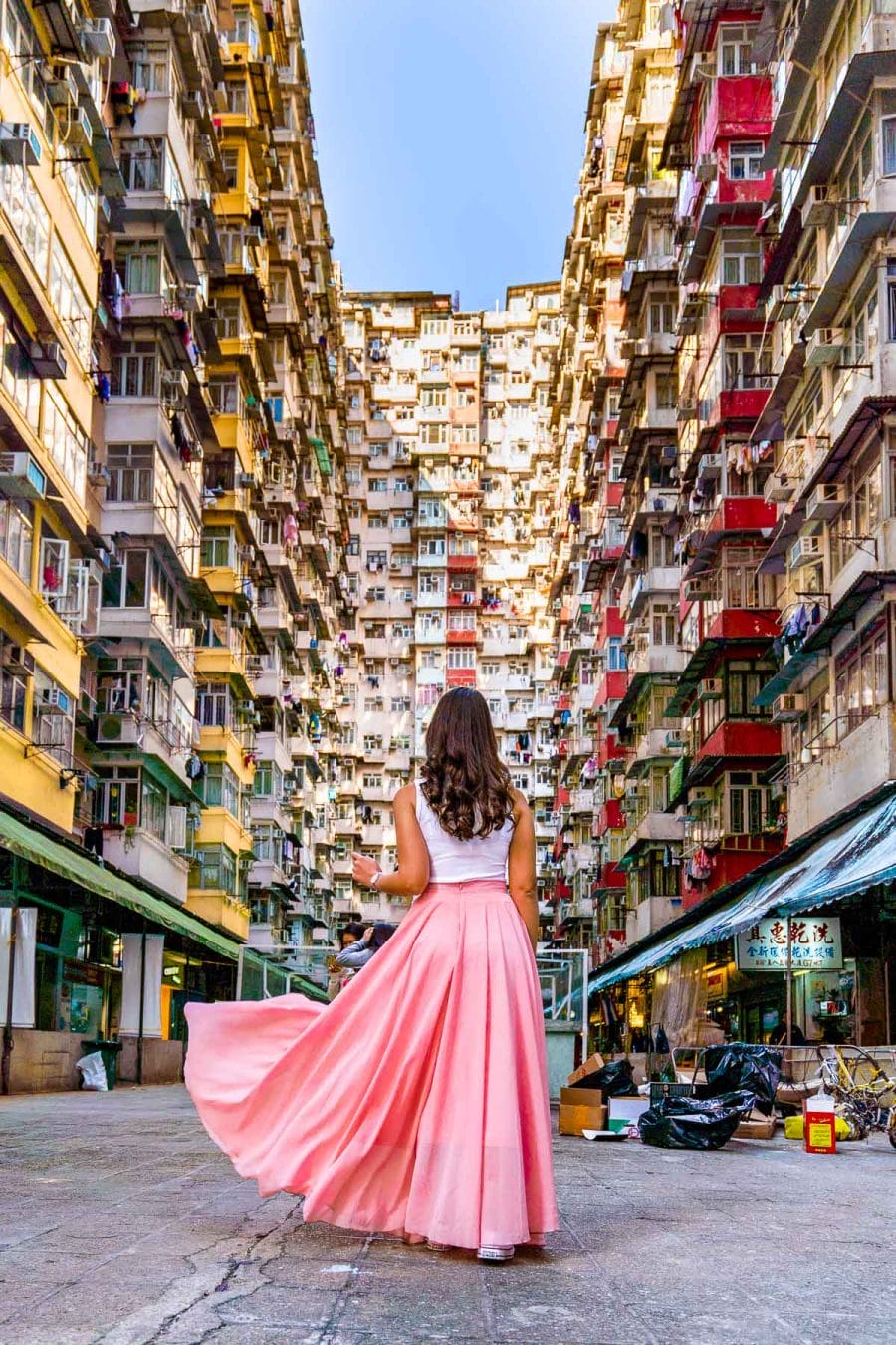 Girl in a pink skirt standing in front of Fok Cheok Building, aka the Monster building in Hong Kong