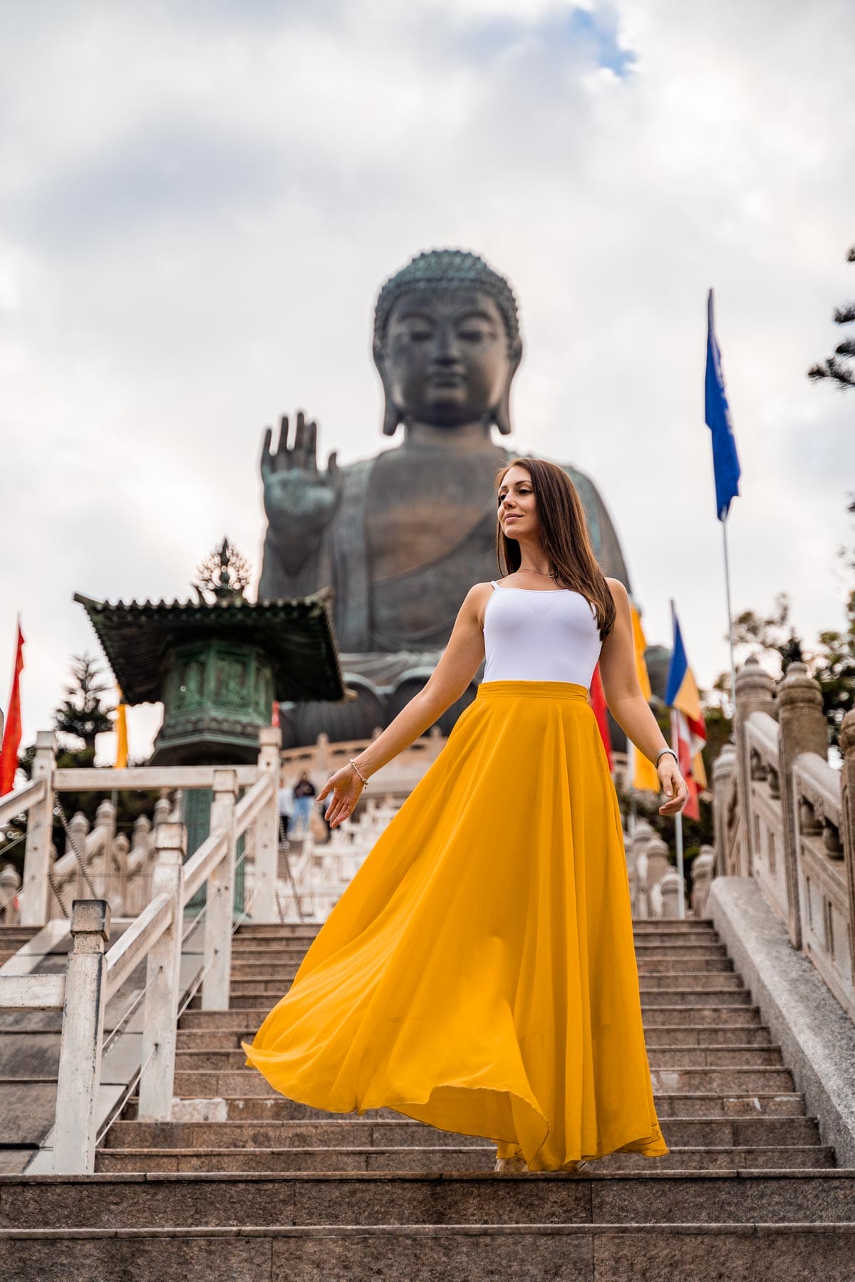 Girl in a yellow skirt standing in front of Tian Tan Buddha in Hong Kong