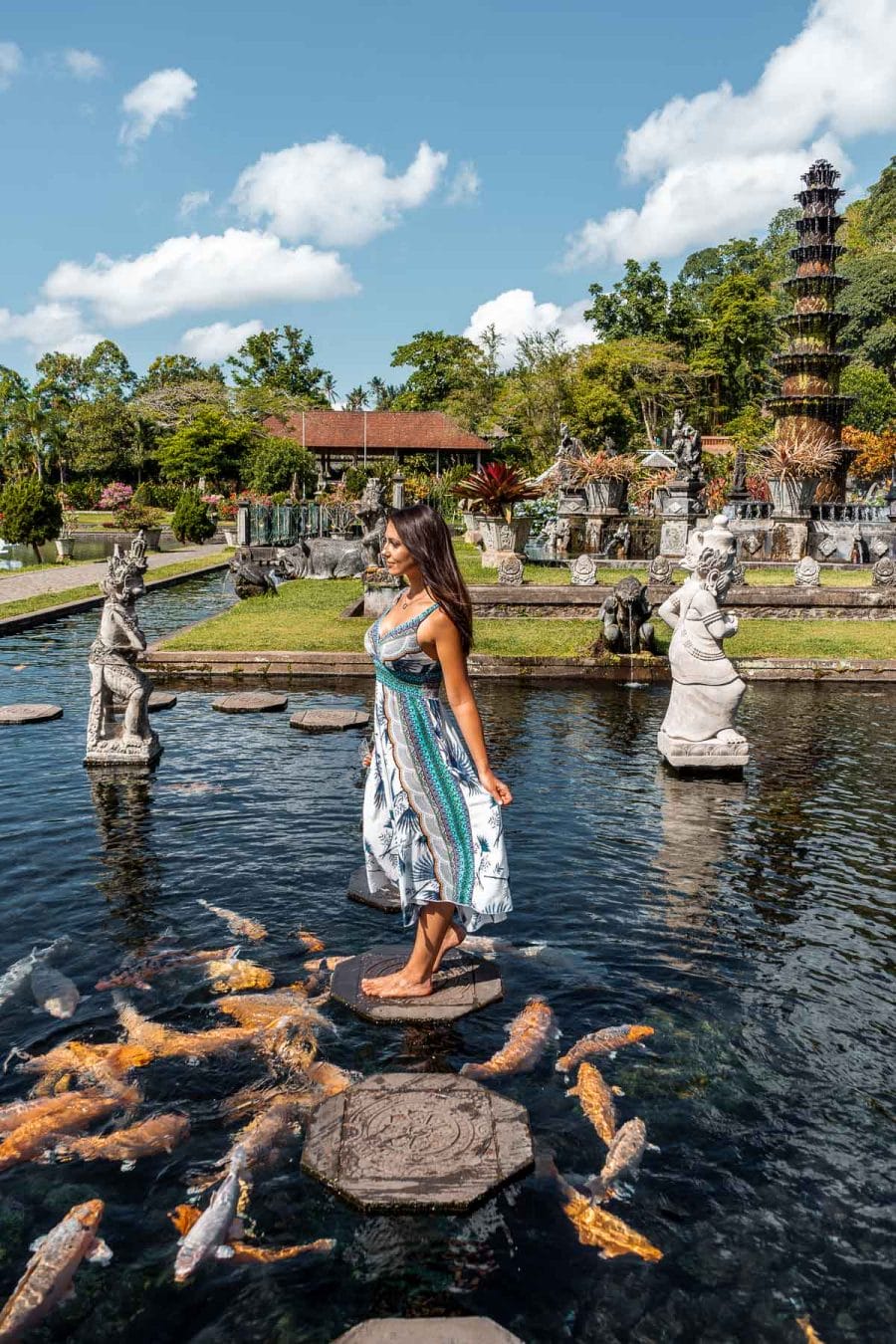 Girl in a blue-white dress standing in the middle of the pool at Tirta Gangga Royal Water Garden in Bali