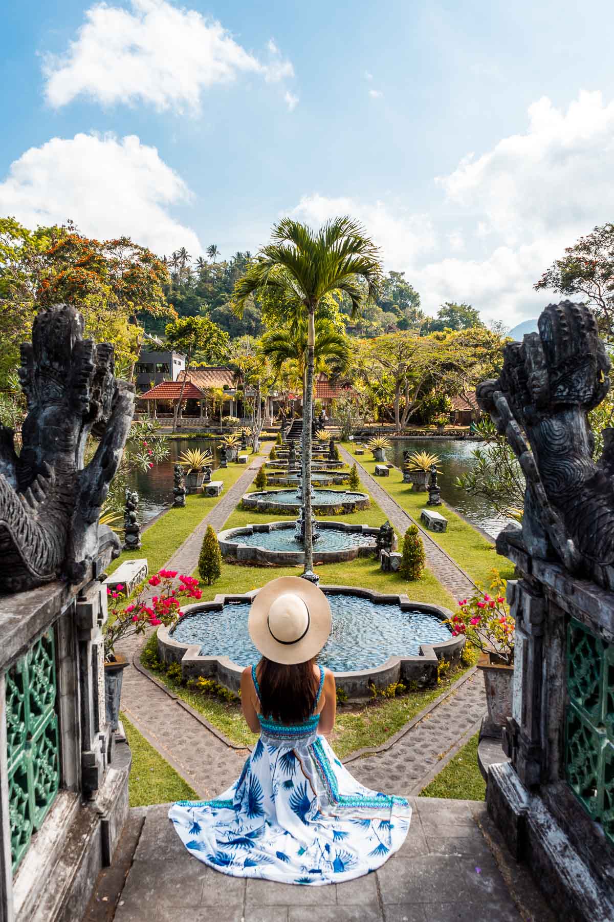 Girl in a blue-white dress sitting on the stairs at Tirta Gangga Royal Water Garden in Bali