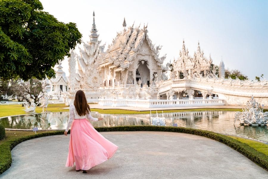 Girl in a pink skirt twirling in front of Wat Rong Khun, the White Temple in Chiang Rai