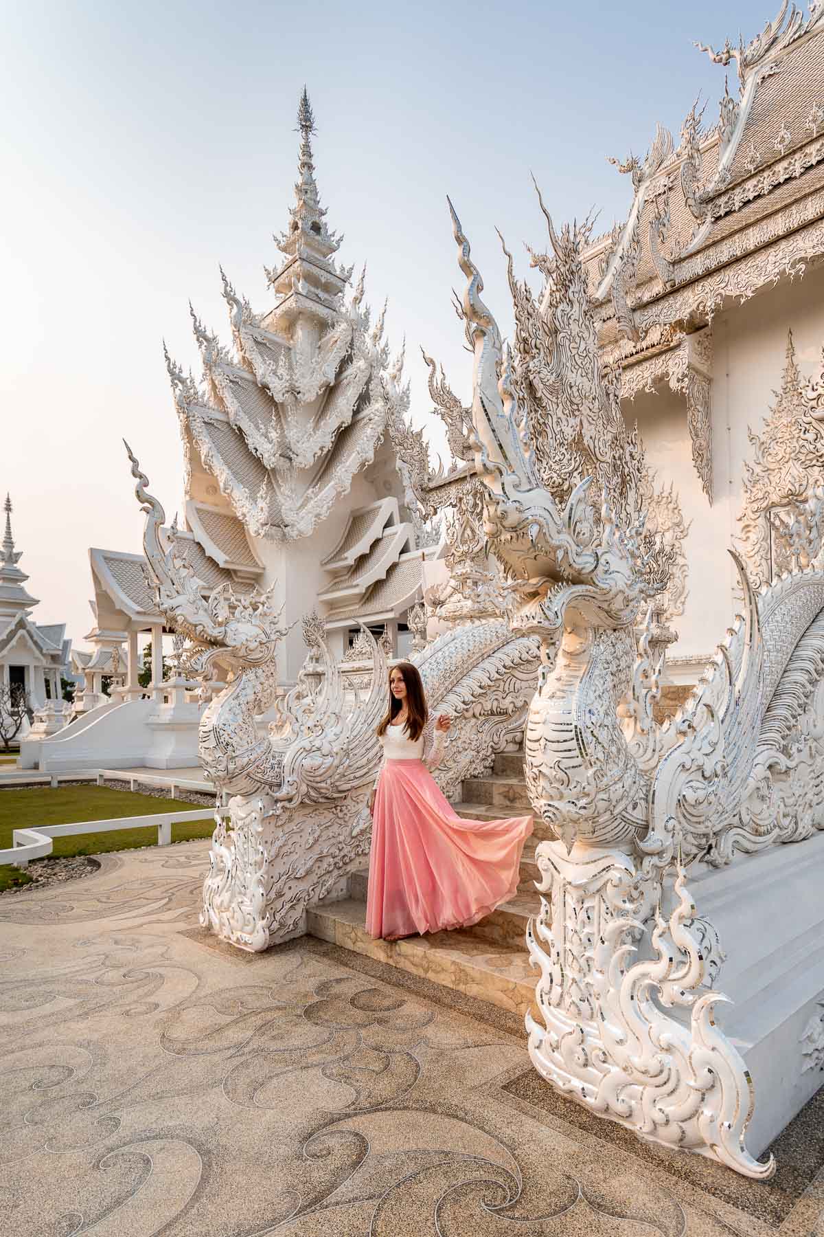 Girl in a pink skirt standing on the stairs in front of Wat Rong Khun, the White Temple in Chiang Rai