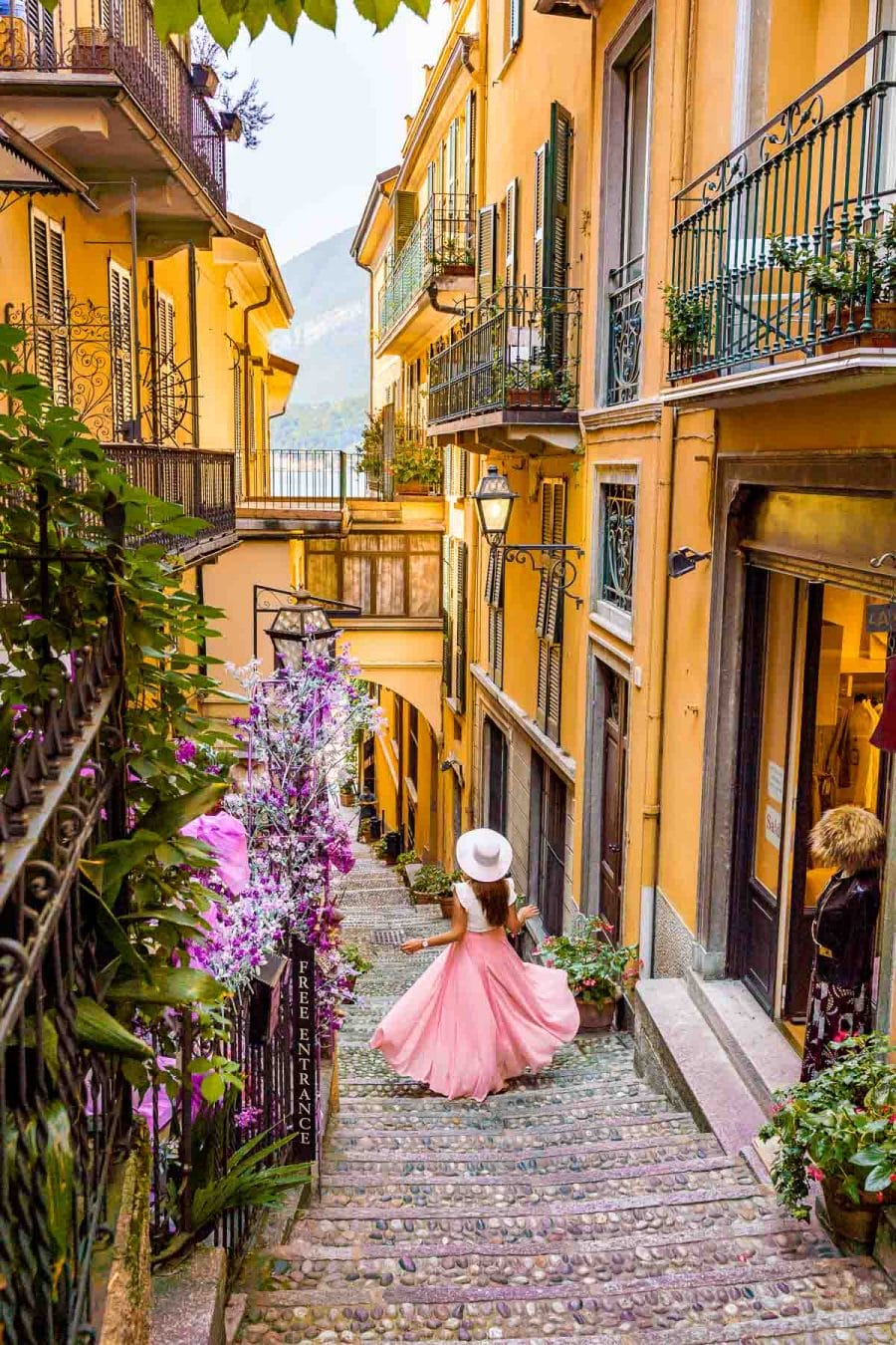 Girl in a pink skirt twirling on a colorful street in Bellagio, Lake Como
