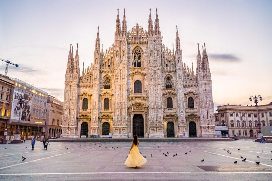 Girl in a yellow dress twirling in front of the Duomo di Milano in Italy