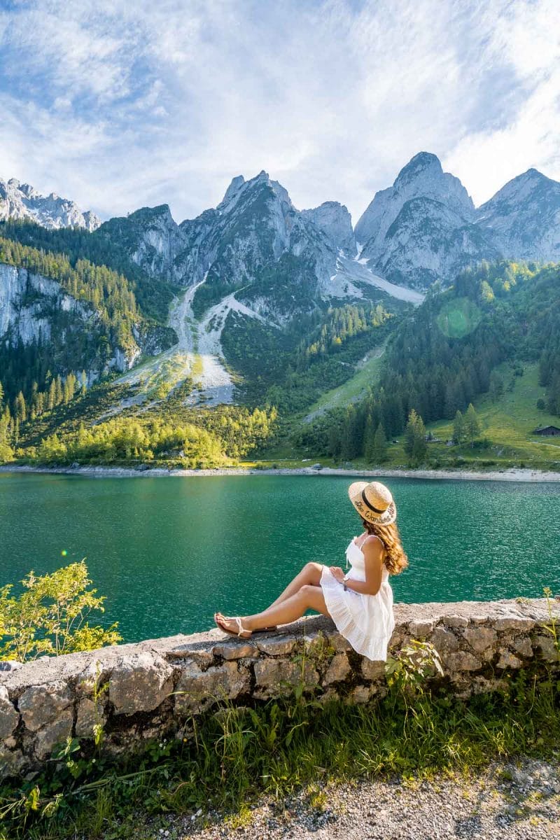 Girl in a white dress sitting on the shores of Gosauseen, Austria