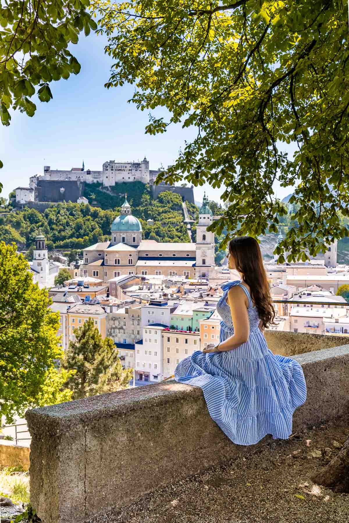 panorámás kilátás Salzburgra a Kapuzinerkloster nézőpontból, kék ruhás lánnyal