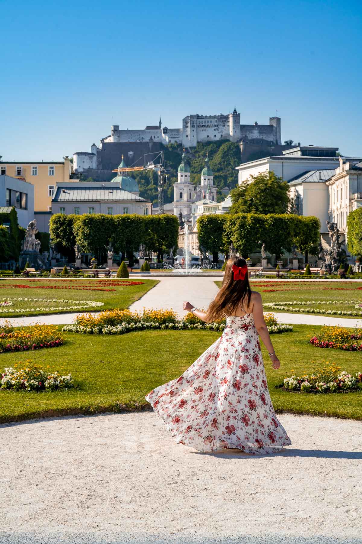 Menina em um vestido floral girando em Jardins Mirabell, Salzburgo