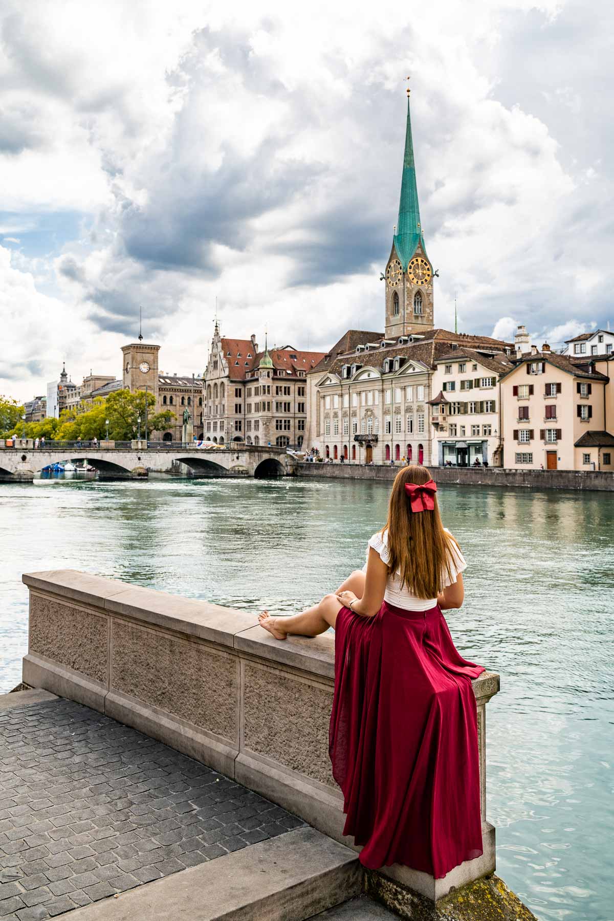 Girl in a red skirt sitting by the riverwalk in Zurich, Switzerland