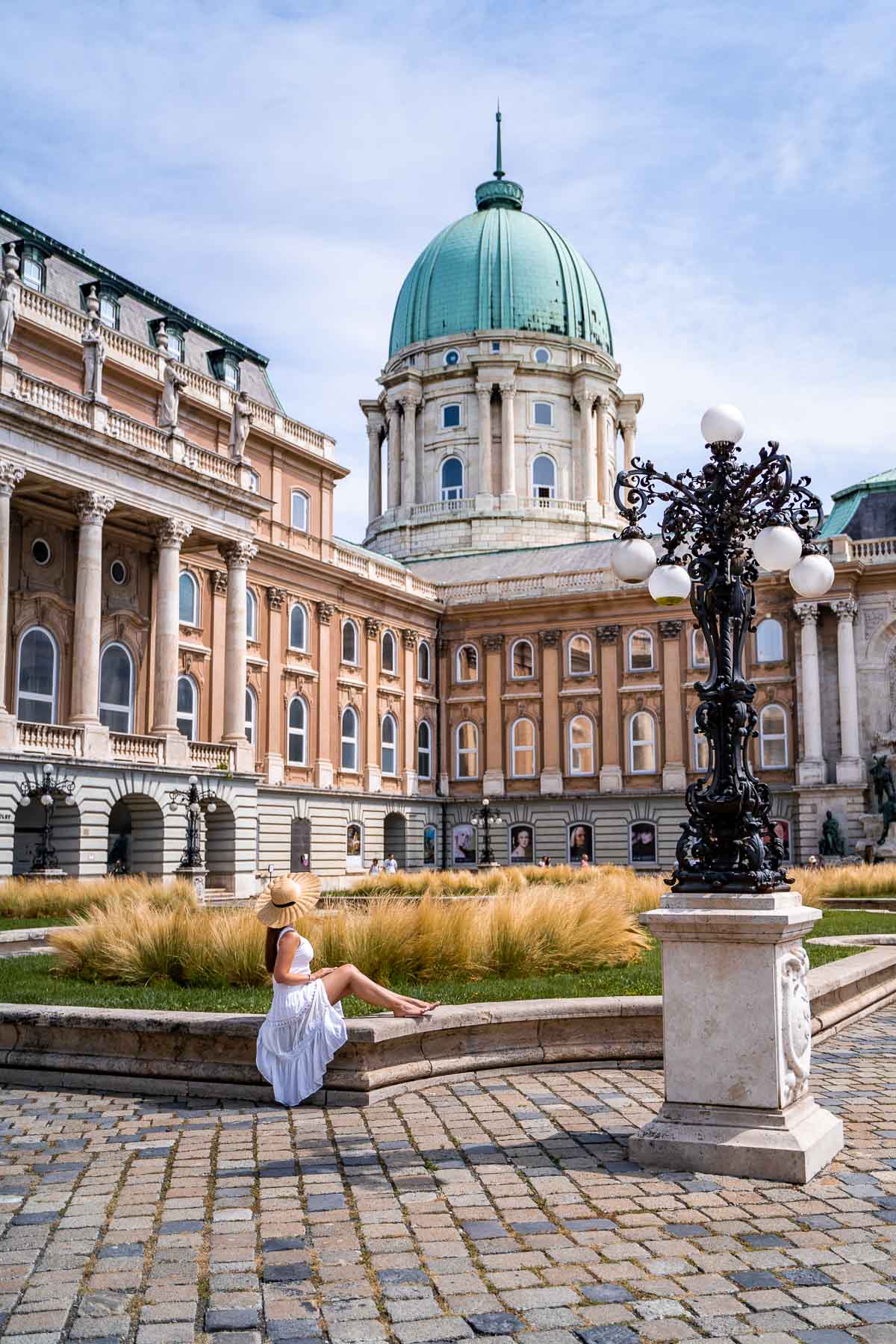 Girl in a white dress sitting in front of Buda Castle